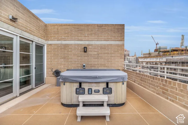 Rooftop patio with a spa, brick perimeter wall, and sliding glass doors