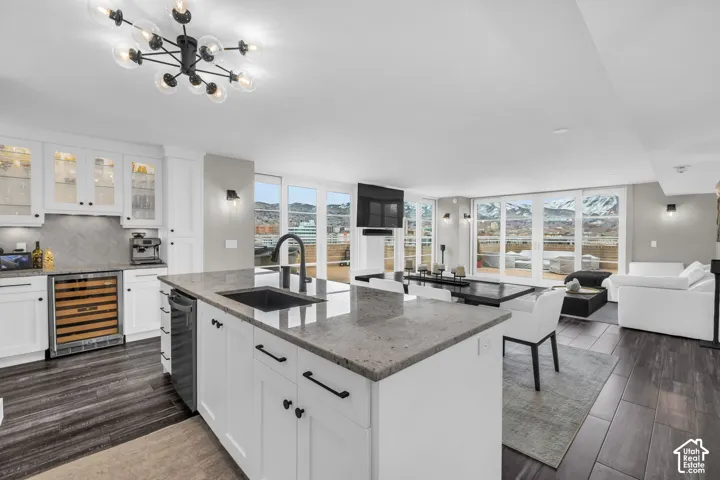 Open concept living space featuring wood-finish flooring, white cabinetry, and an island with an undermount sink