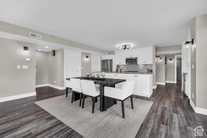Open concept living space featuring wood-finish flooring, white cabinetry, and recessed lighting