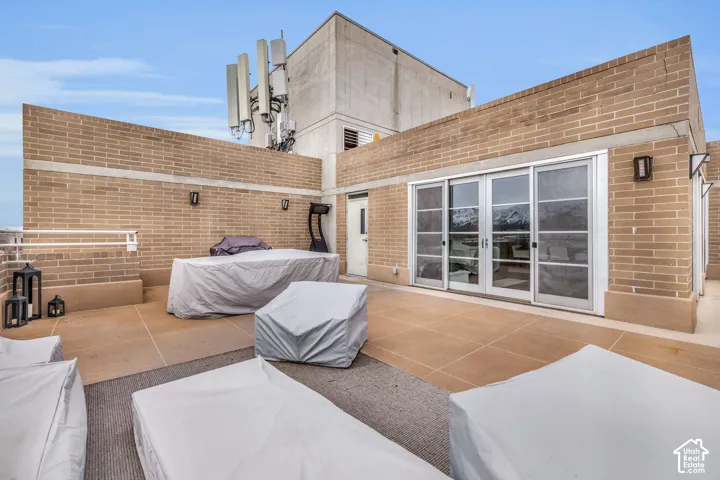 Expansive rooftop terrace featuring brick walls, an exterior door, and a multi-panel sliding glass door