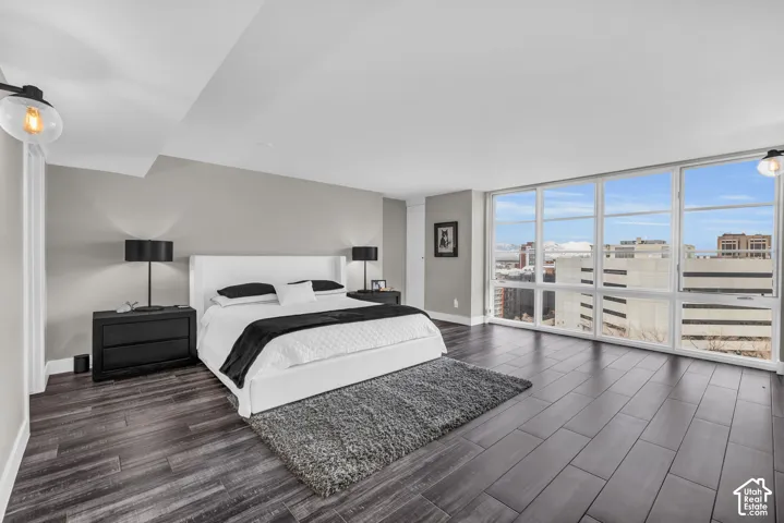 Expansive room featuring floor-to-ceiling windows, wood-finish flooring, recessed lighting, and wall sconces