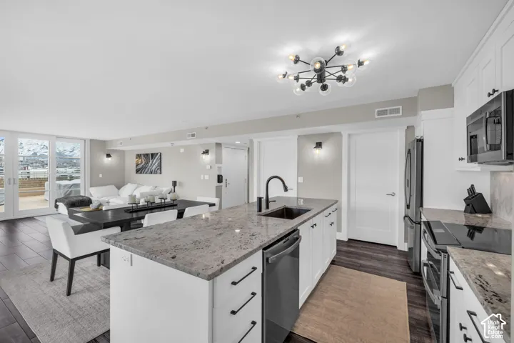 Gourmet kitchen with granite countertops, integrated stainless steel appliances, and a central island with sink