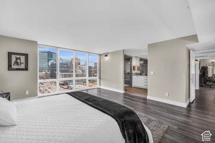 Expansive floor-to-ceiling windows, dark wood-finish flooring, recessed lighting, and a white vanity with dual sinks