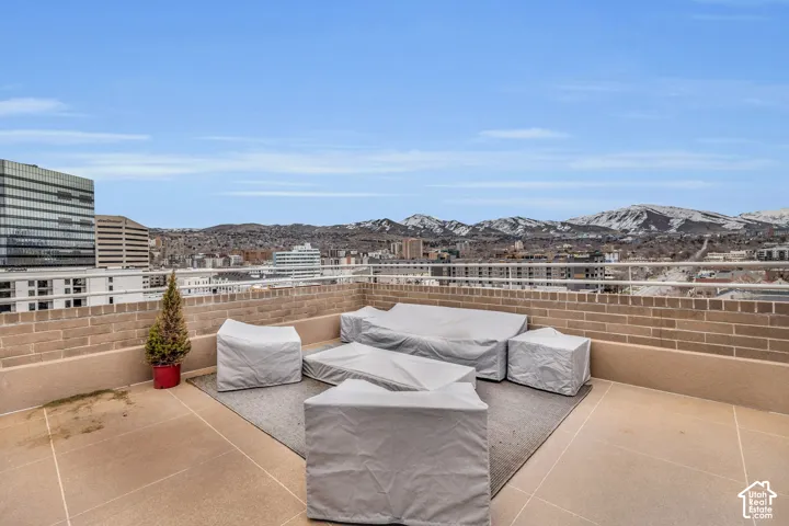 Expansive outdoor terrace with brick wall, metal railing, and city skyline
