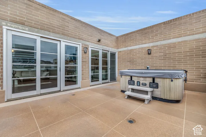 Expansive outdoor patio featuring a hot tub, brick privacy walls, and multiple sets of glass-paneled sliding doors