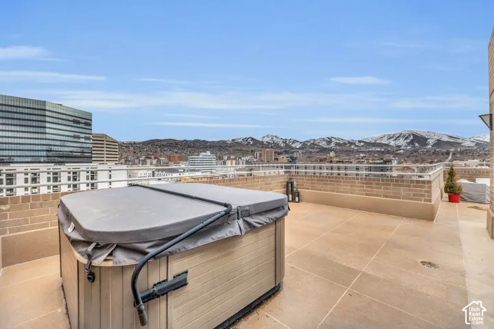 Rooftop terrace with a hot tub, brick privacy walls, and a durable hardscape surface