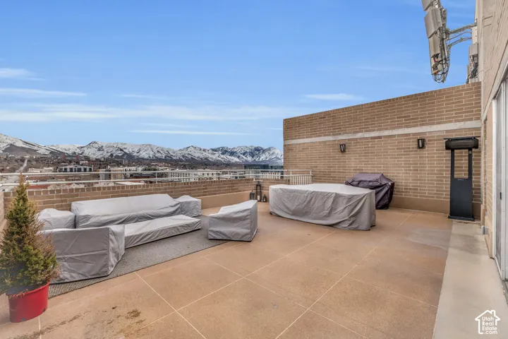 Expansive rooftop terrace with brick privacy wall, outdoor wall sconces, and mountain scenery