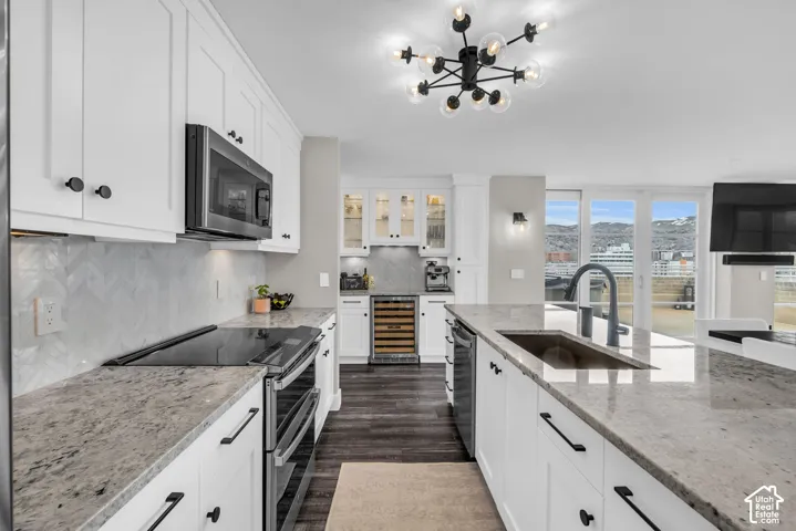 White shaker-style cabinetry with black hardware, stone countertops, a subway tile backsplash, and stainless steel appliances