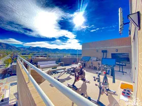 Expansive rooftop terrace with mountain backdrop, featuring a built-in outdoor kitchen, dedicated exercise space, and a distinct lounge area