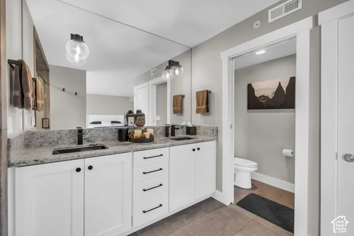 Dual vanity with integrated sinks, white cabinetry, granite-style countertop, and matte black fixtures
