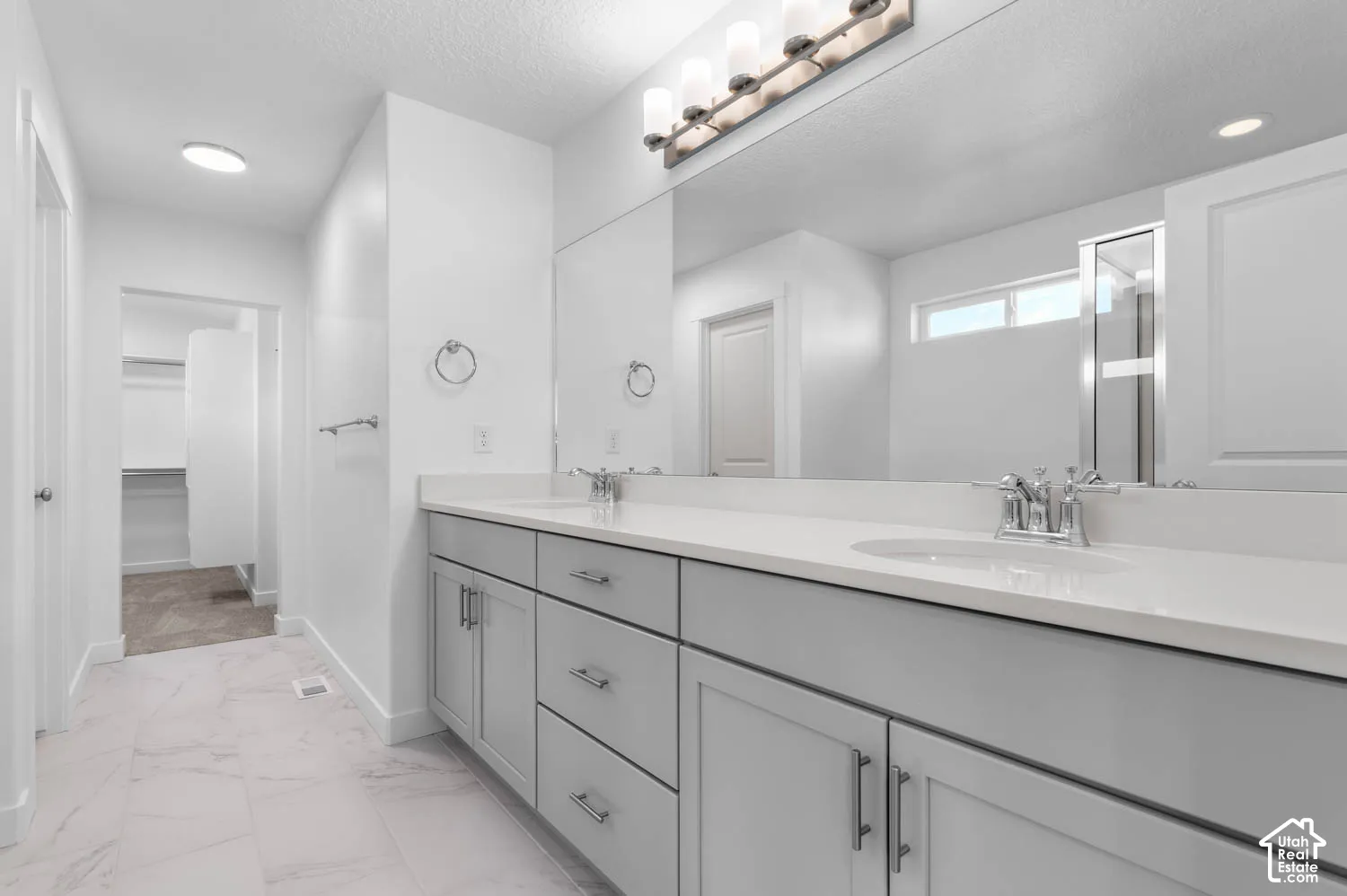 Double vanity with light gray cabinetry, integrated sinks, white countertops, and chrome fixtures
