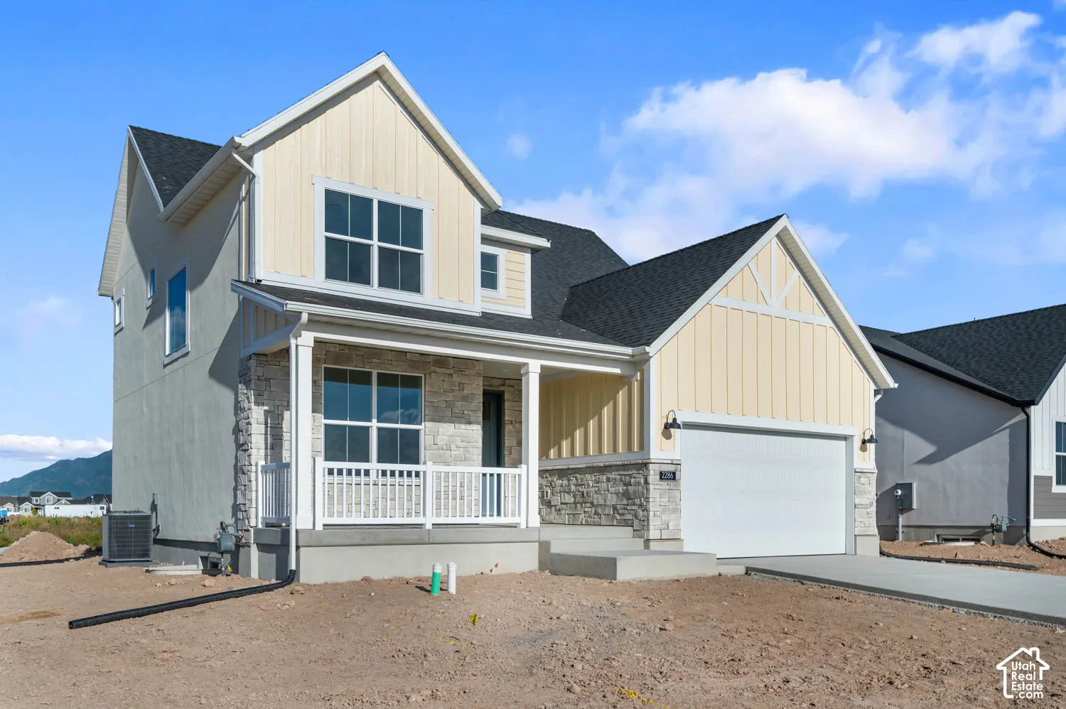 Contemporary two-story exterior with stone and siding accents, a covered front porch, and a two-car garage