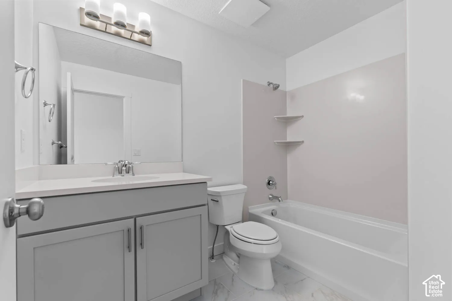 Contemporary bathroom featuring a light gray vanity with a single basin sink, a wall-mounted mirror, a tub/shower combination, and marble-look floor tiling