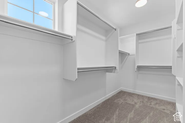 Walk-in closet featuring built-in shelving, hanging rods, and a window