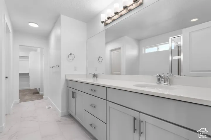 Double vanity with light gray cabinetry, integrated sinks, white countertops, and chrome fixtures