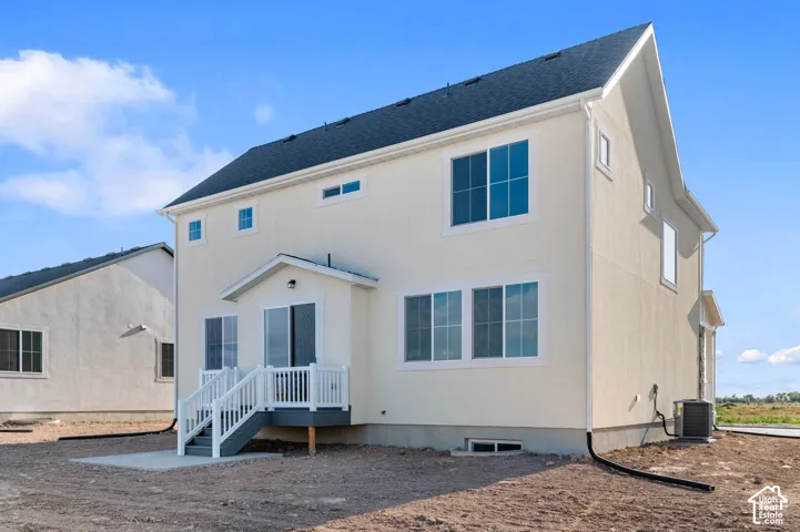 Stucco exterior with multiple windows, covered deck, and exterior stairs
