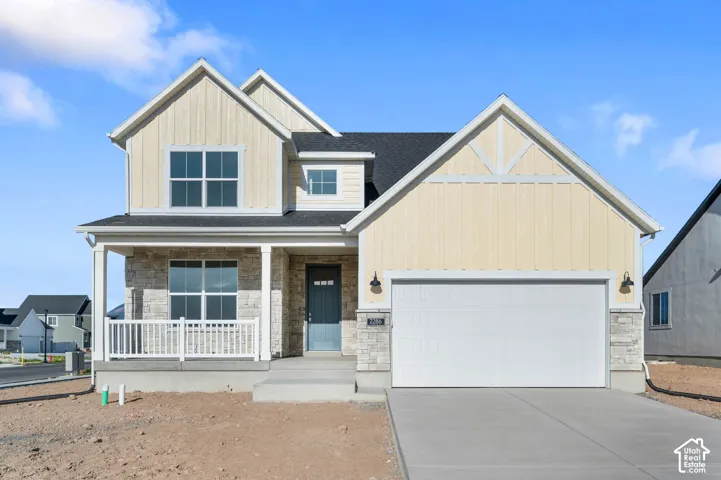 Gabled roofline with light-colored siding and stone accents, covered front porch with white railings, front entry door with three window panes, attached garage with white door, and concrete driveway