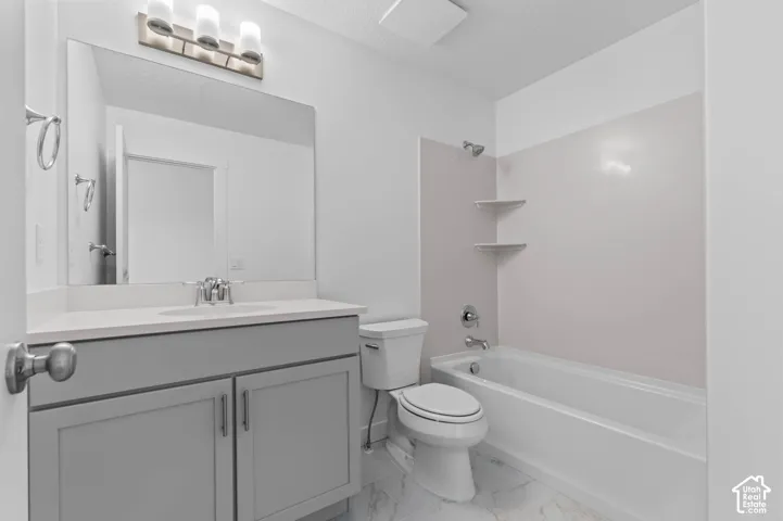 Contemporary bathroom featuring a light gray vanity with a single basin sink, a wall-mounted mirror, a tub/shower combination, and marble-look floor tiling