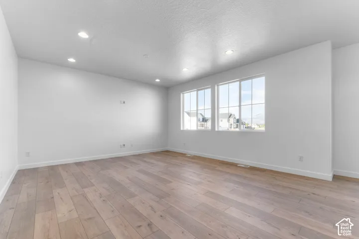 Spacious room featuring wood-finish flooring, recessed lighting, and dual multi-pane windows