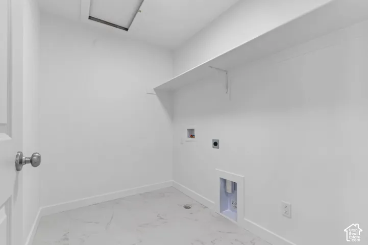 White interior walls with a single shelf, equipped with appliance hookups and a ceiling access panel
