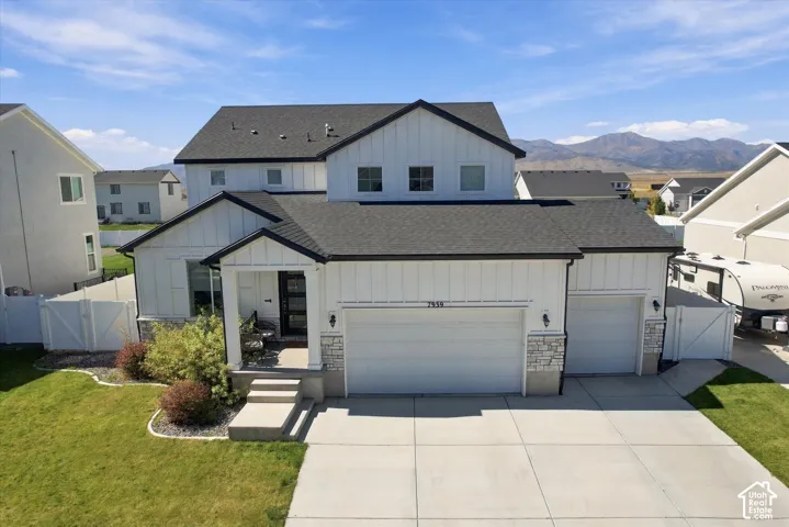 Modern exterior siding with board and batten accents, a dark asphalt shingle roof, a two-car garage, stone veneer detailing, and a concrete driveway