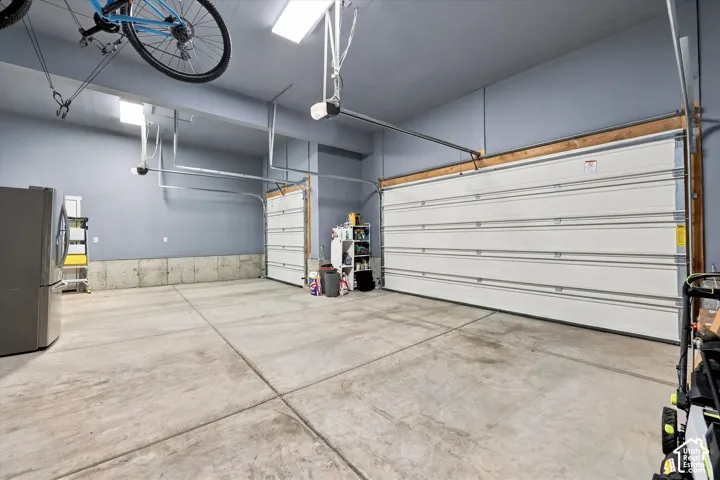 Attached garage with concrete flooring, two overhead garage doors, and overhead lighting