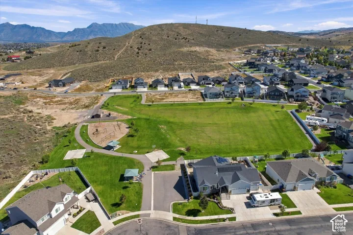 Expansive green space featuring a playground, paved walking paths, and shaded picnic areas