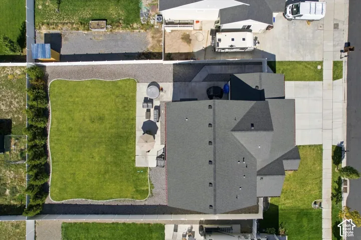 Expansive backyard with a manicured lawn, established landscaping, and a concrete patio