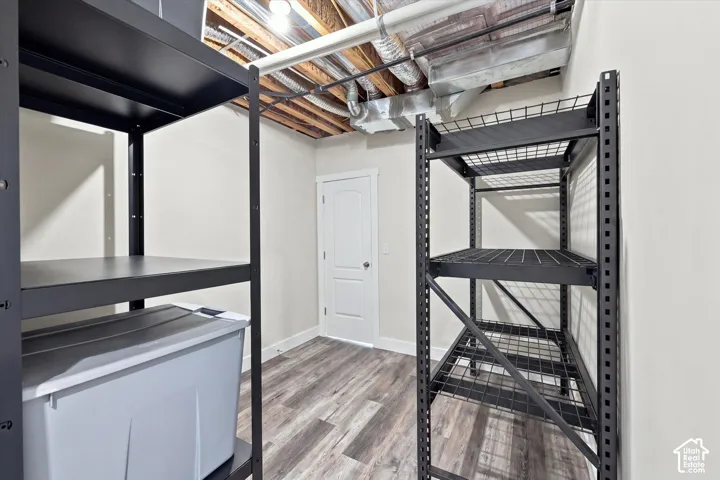 Utility space featuring durable shelving units and wood-finish flooring