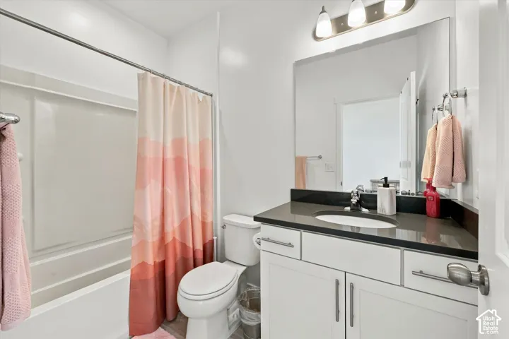 Bathroom featuring a white vanity with brushed nickel hardware, an integrated sink, a dark countertop, and a shower-over-tub combination