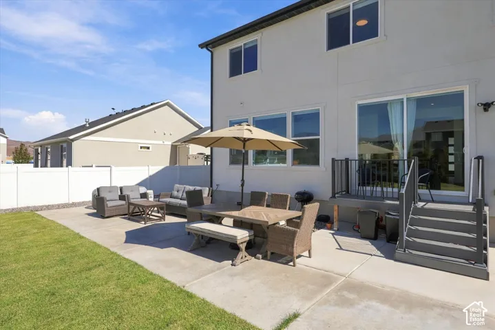 Rear exterior featuring a concrete patio, a raised deck with stairs, and a sliding glass door