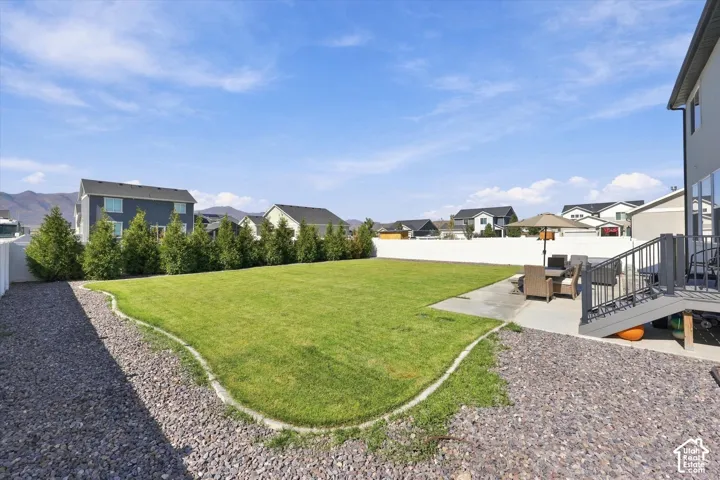 Expansive grassy yard with a concrete patio, composite deck, and privacy fencing