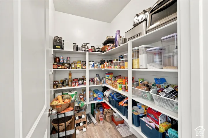 Spacious pantry featuring extensive built-in shelving, white finish, and wood-finish flooring