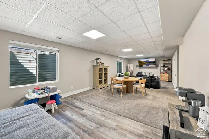 Recessed lighting, wood-finish flooring, light grey carpeting, egress window, and white trim