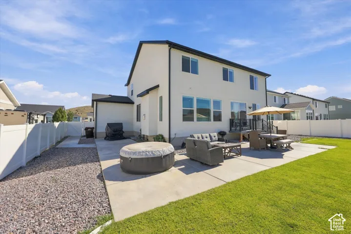 Expansive concrete patio with direct backyard access, bordered by a manicured lawn and a gravel-covered side yard