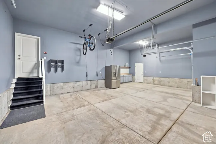 Spacious garage with light blue walls, concrete flooring, built-in cabinetry, and overhead lighting