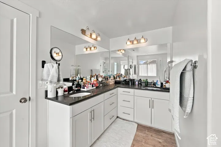 Dual vanity with white cabinetry, dark countertops, and integrated sinks