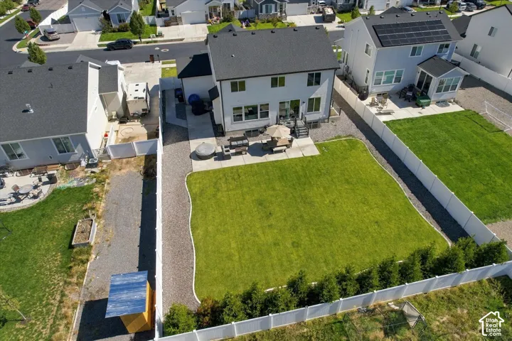 Expansive backyard featuring a manicured lawn, concrete patio, and gravel pathways