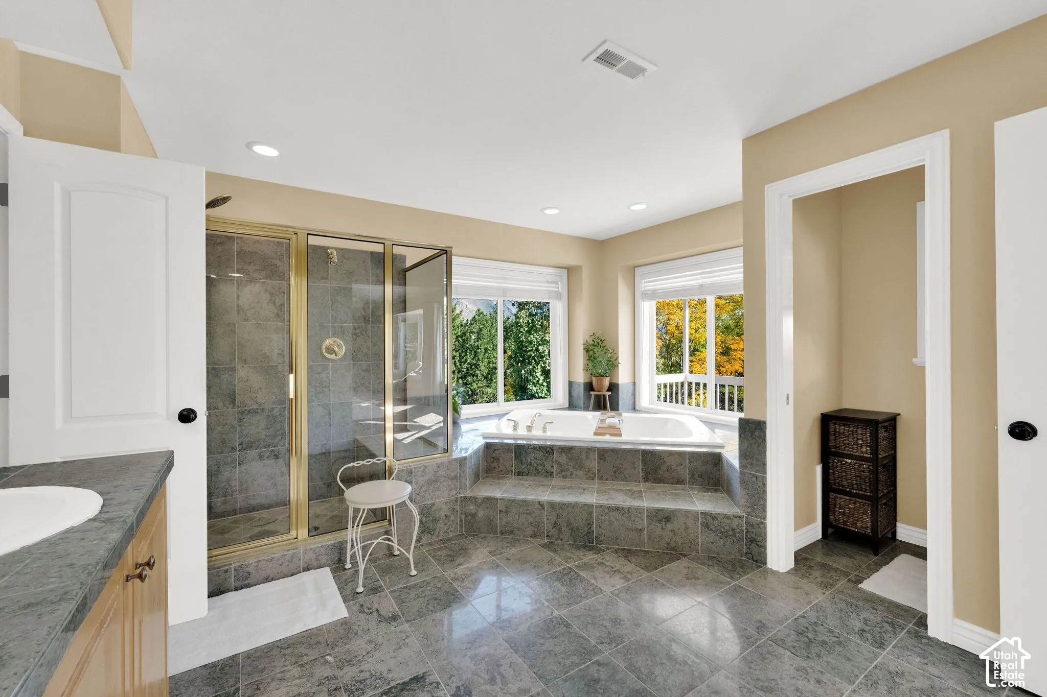 Recessed lighting, step-up bathtub platform, built-in soaking tub, glass-enclosed shower, and large windows