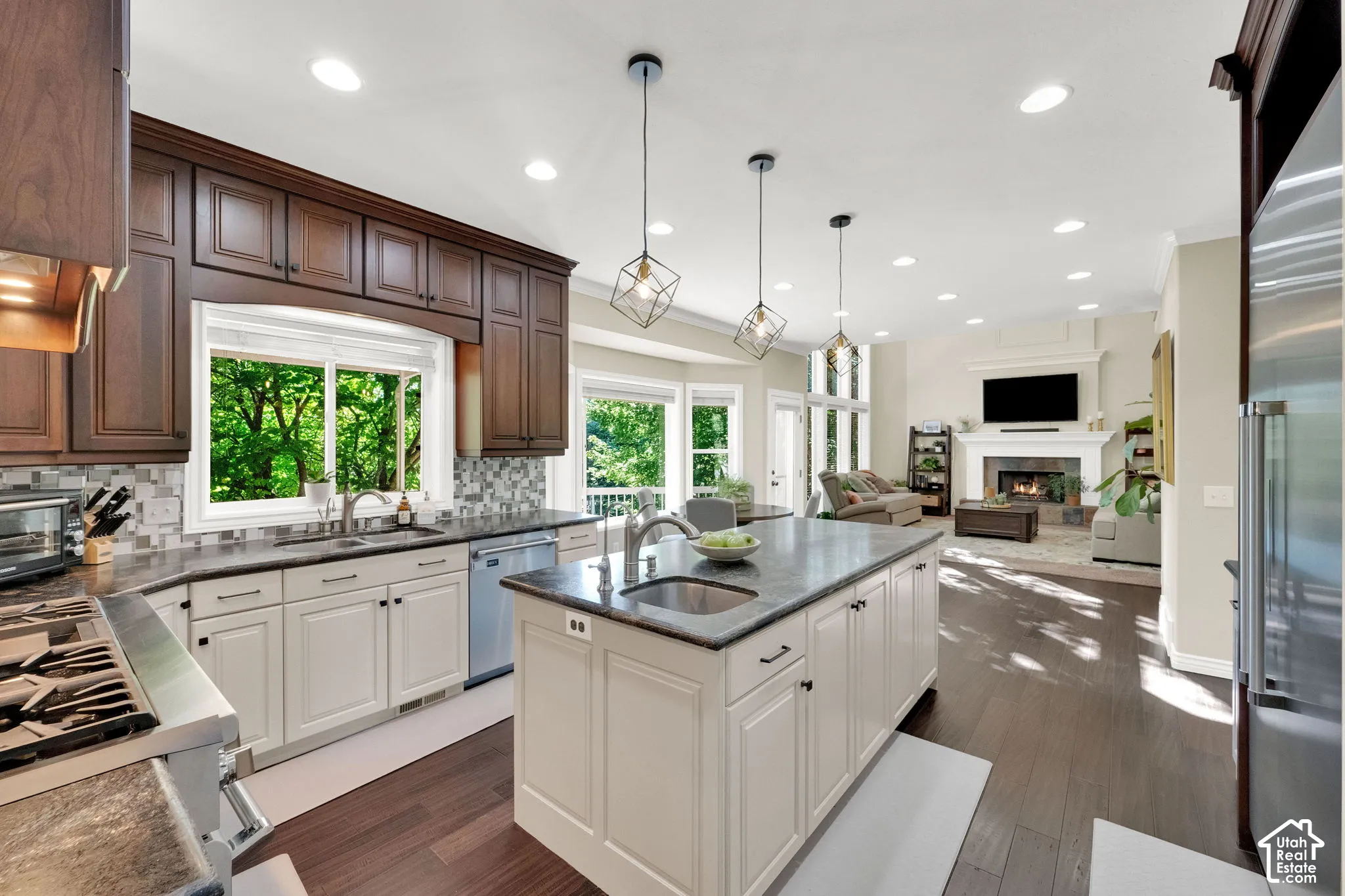 Kitchen featuring wood-finish flooring, two-tone cabinetry, a central island with a sink, stainless steel appliances, and recessed lighting