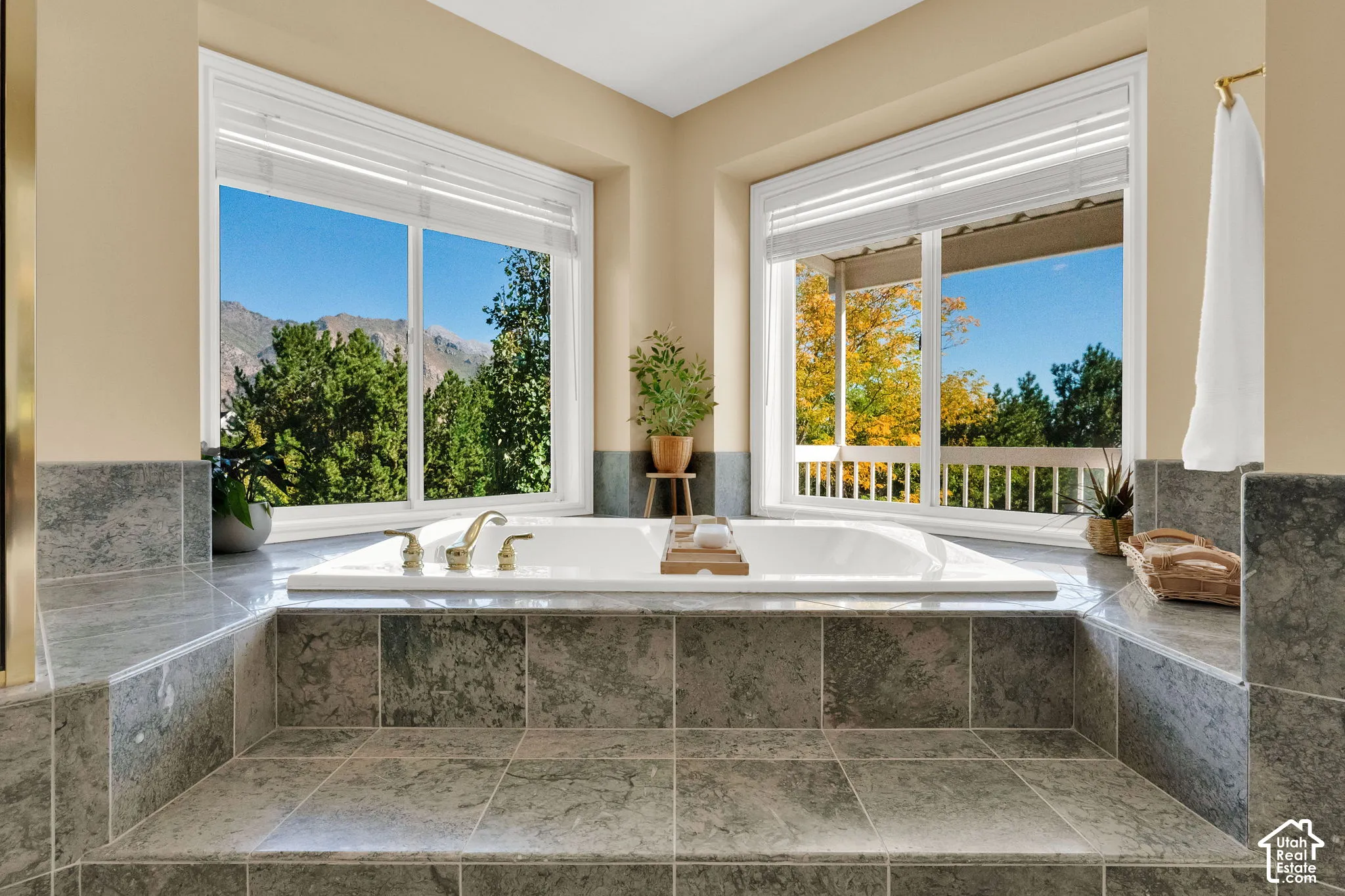 Built-in soaking tub with deck-mounted fixtures, surrounded by grey tile flooring and wall accents