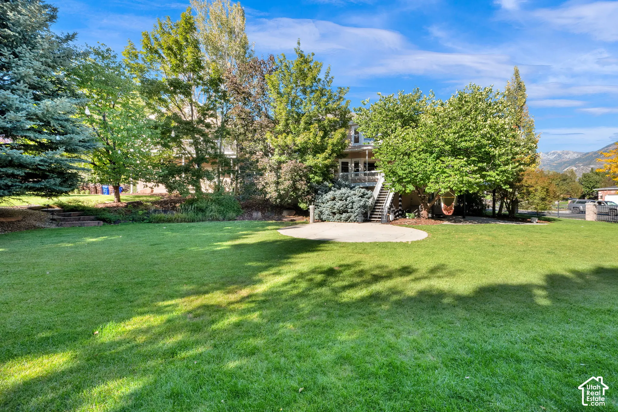 Expansive lawn with mature trees and a circular concrete patio