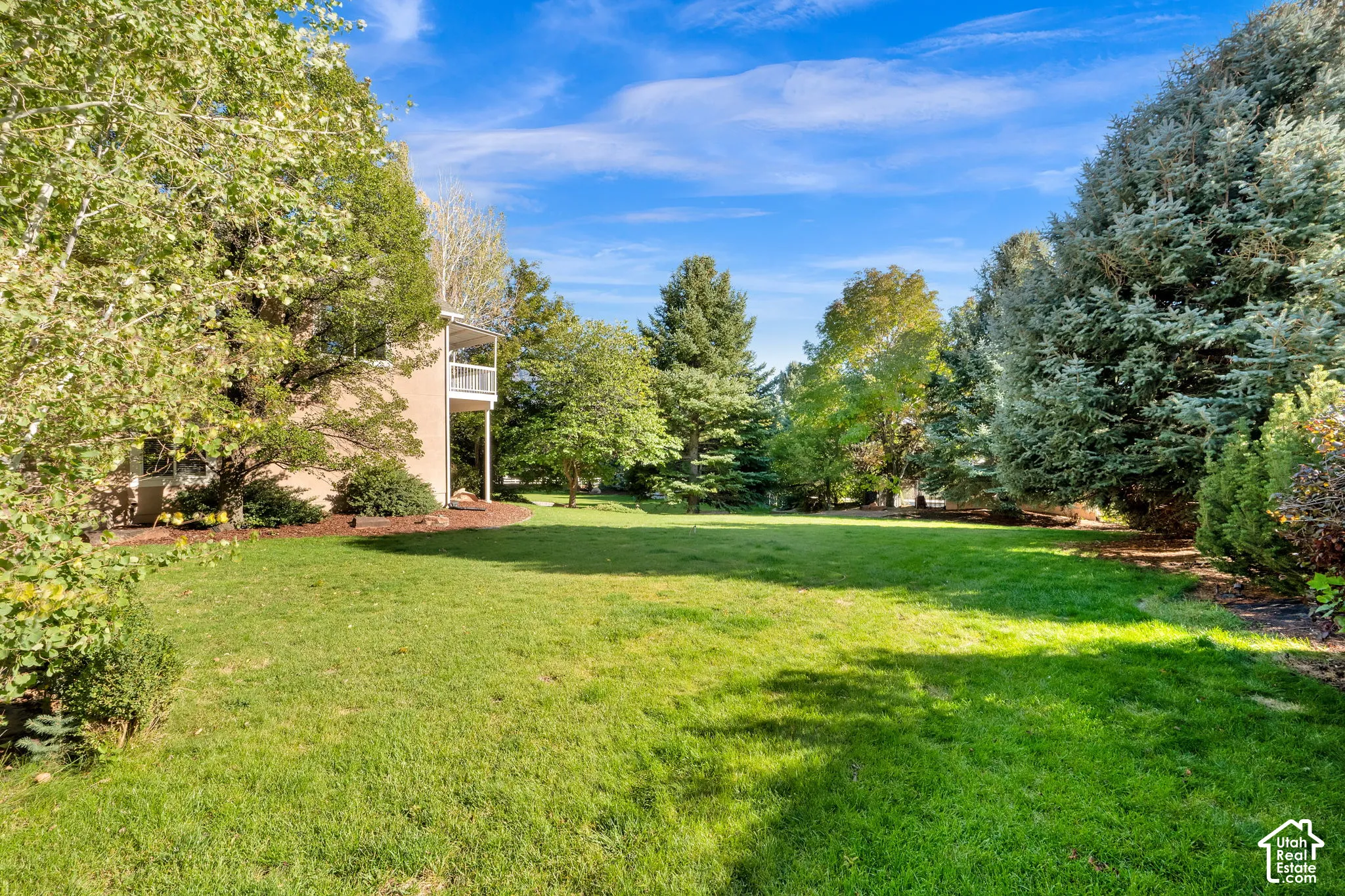 Expansive lawn area bordered by mature trees and varied landscaping