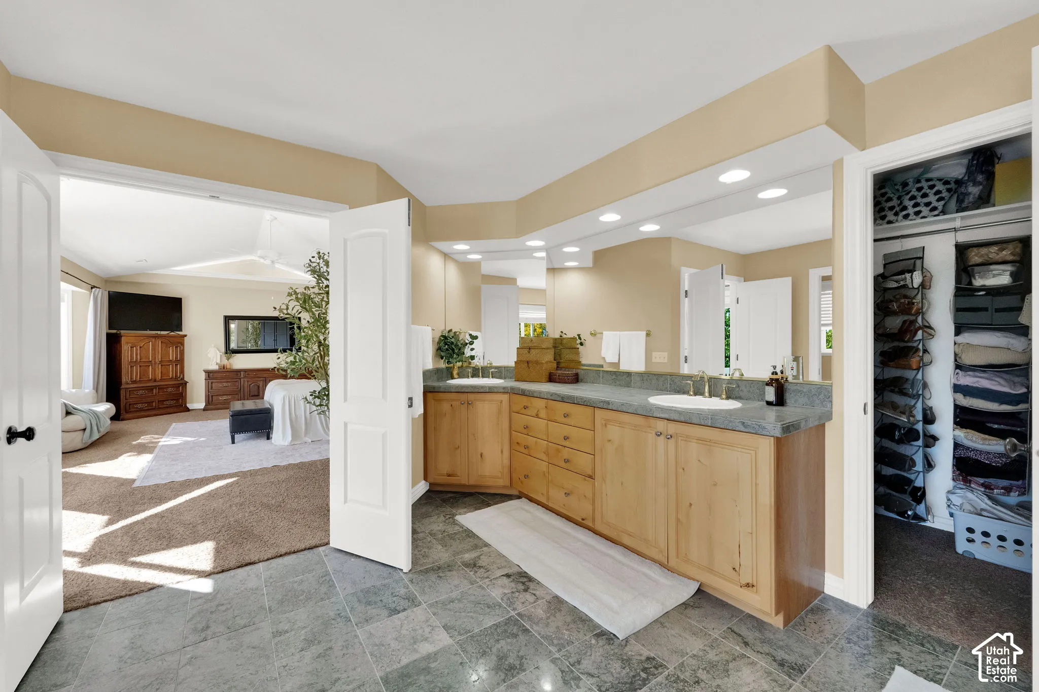 Dual sinks with wood-finish cabinetry, recessed lighting, and a walk-in closet with built-in shelving