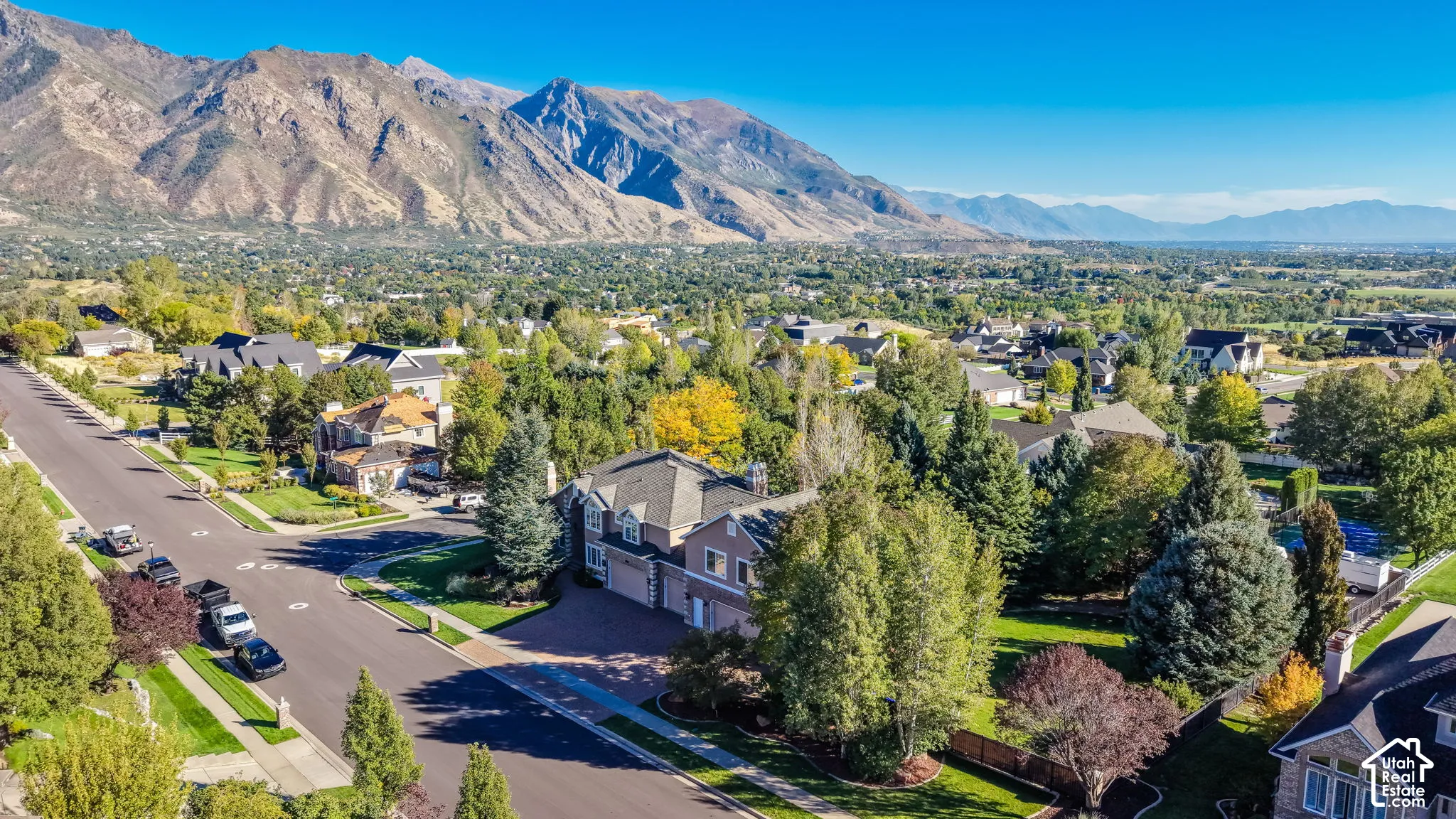 Mountain backdrop, residential neighborhood setting, paved street, mature trees, manicured lawns