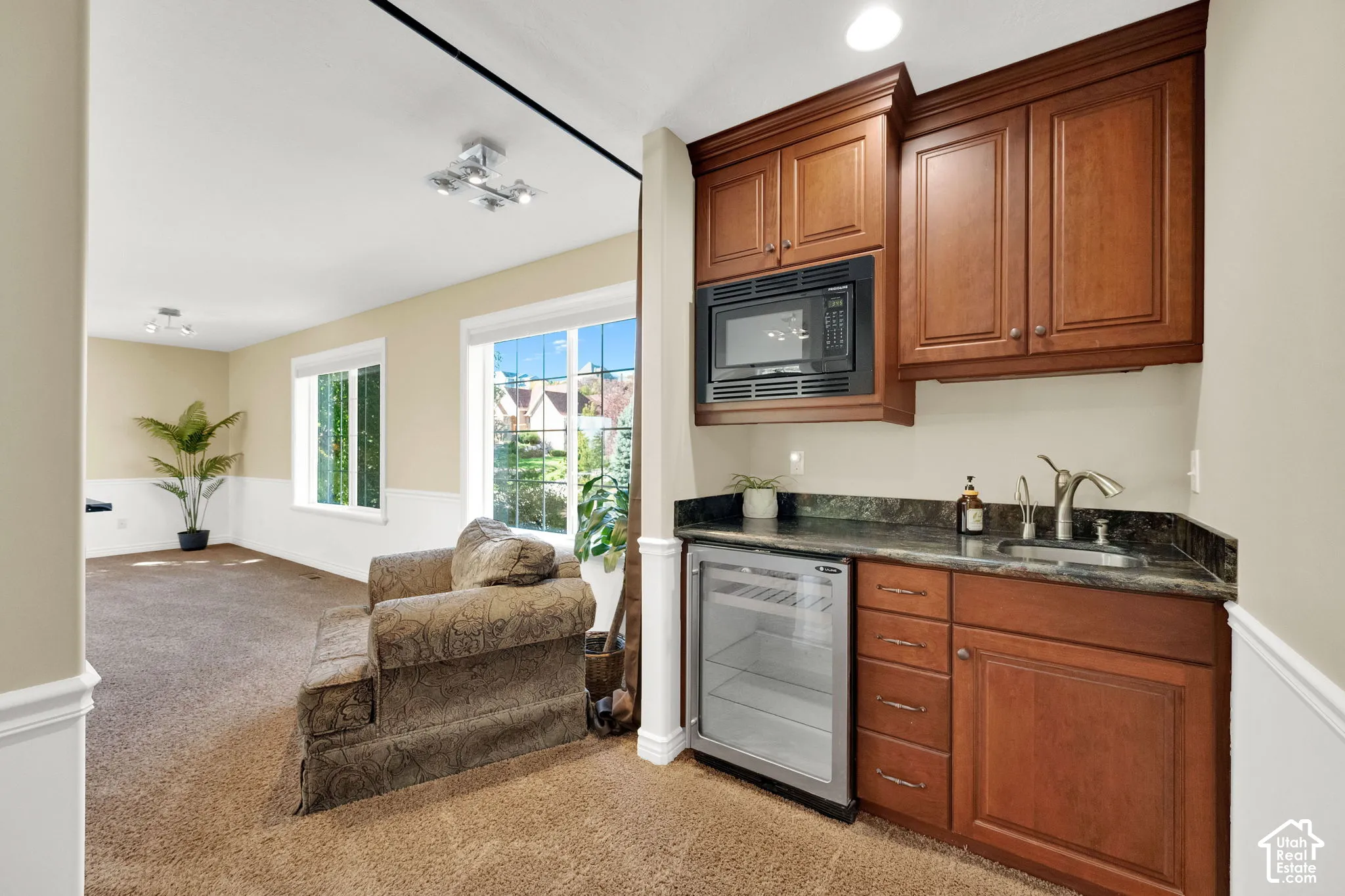 Built-in wet bar with wood cabinetry, dark countertop, and under-counter beverage refrigerator