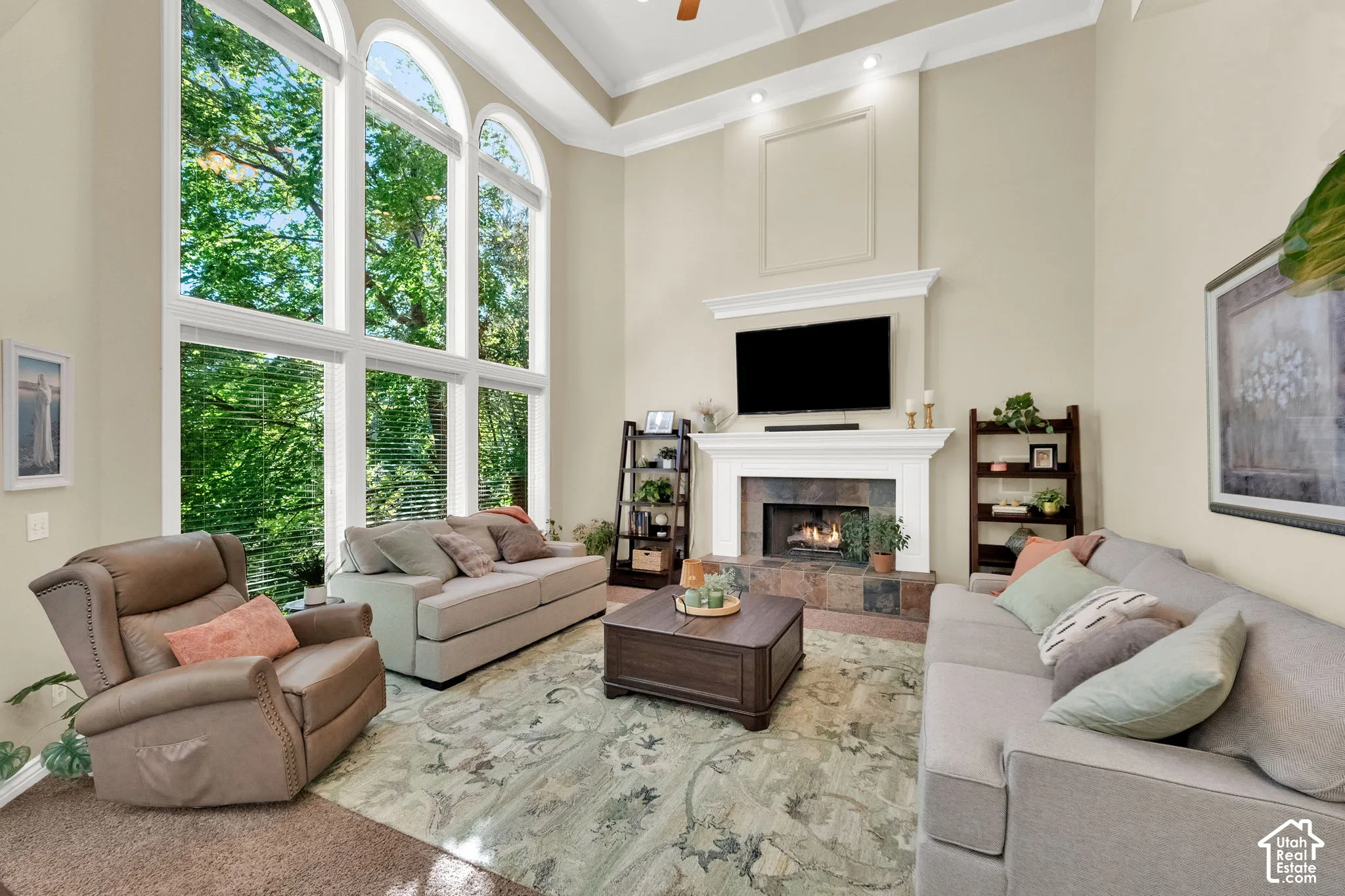 High ceilings with crown molding, a built-in fireplace with a stone surround, and an integrated media mantel