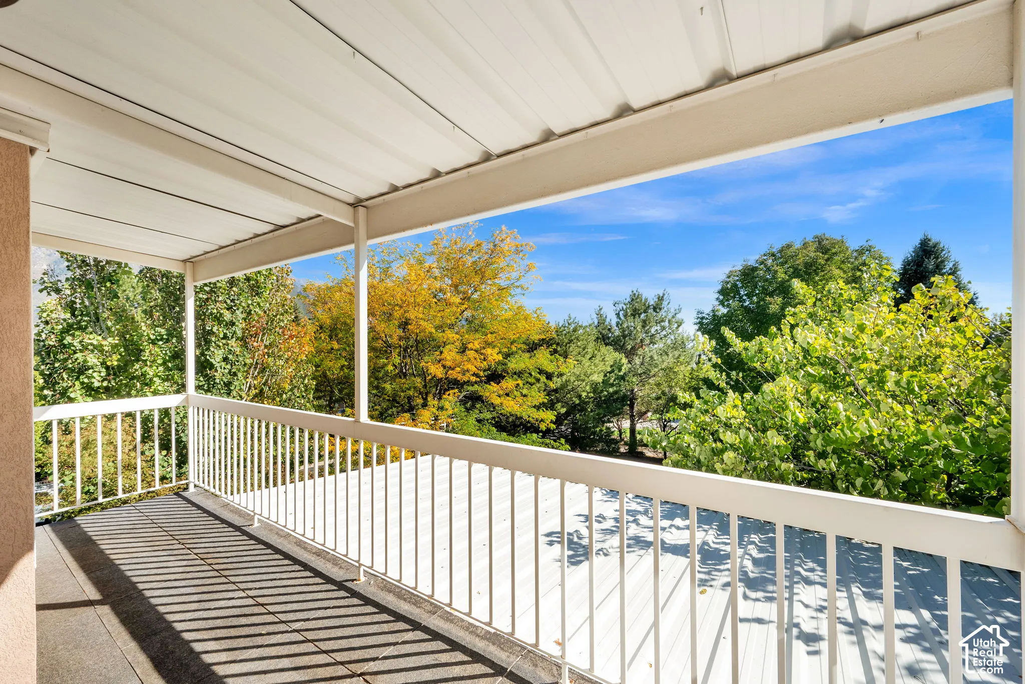 Covered outdoor patio with a metal railing and a tiled floor