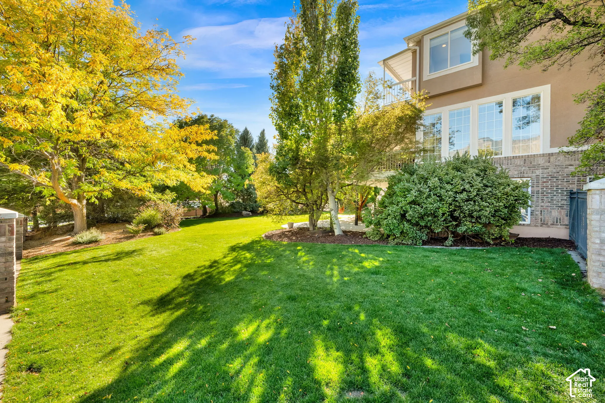 Expansive lawn area with mature trees, stone pillars, and manicured landscaping