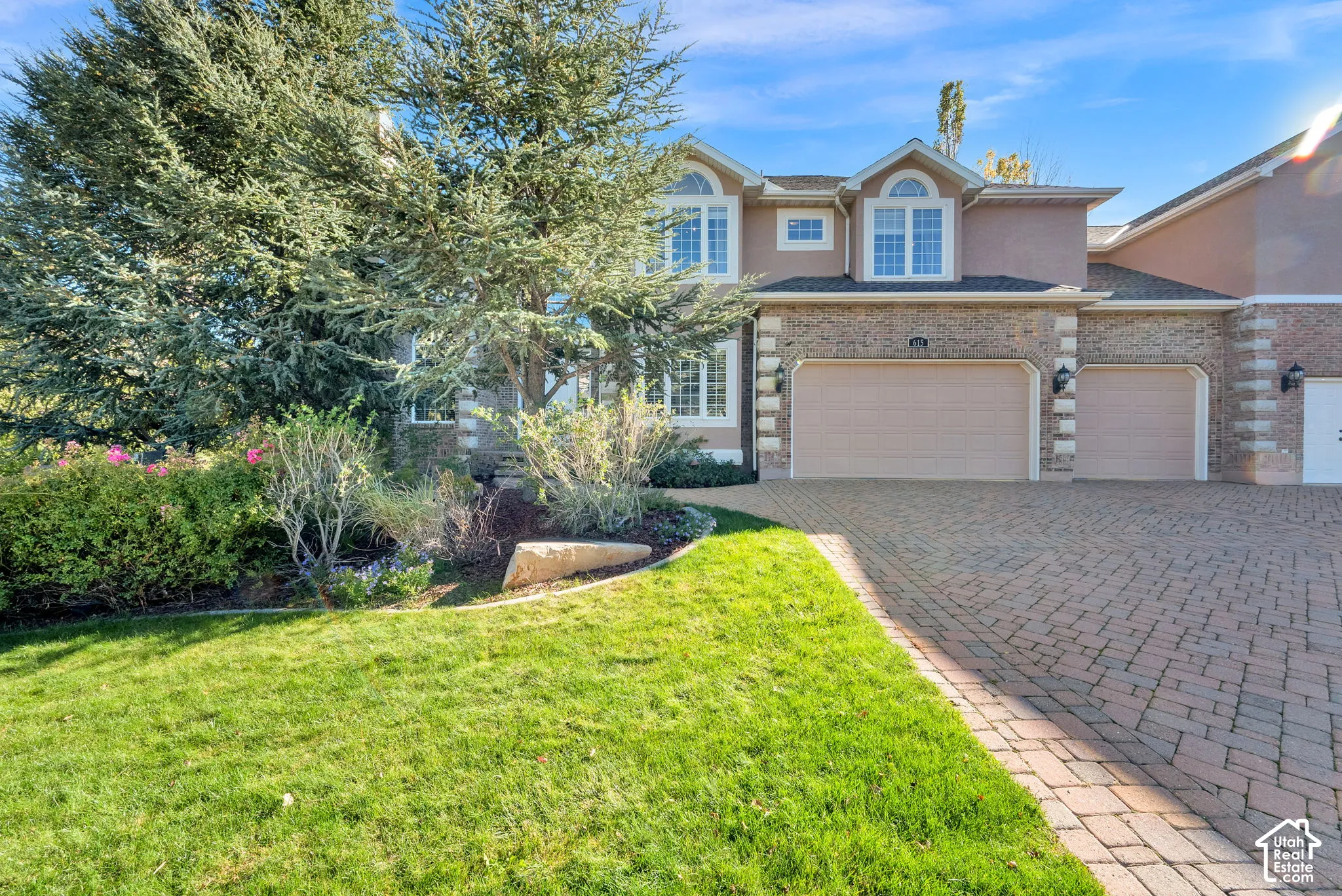 Stucco exterior with brick accents, arched windows, and a paved brick driveway